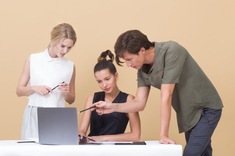 Trzy odoby pochylające się nad projektem w laptopie jednej z nich.